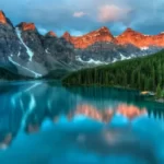 A stunning landscape featuring a mountain, a calm lake, and lush green trees, reflecting the beauty and inspiration found in mountain quotes.