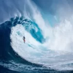 A surfer riding an ocean wave, capturing the adventurous and scenic spirit of Hawaii featured in the quotes.