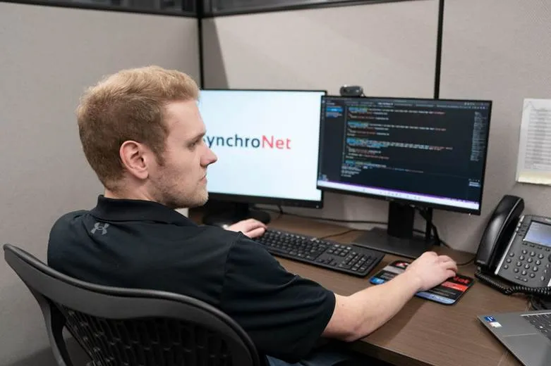 a man working on SynchroNet office desktop computer