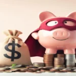 A pink piggy bank dressed as a superhero with a red mask and cape, standing on a stack of coins next to a burlap money bag with a dollar sign.