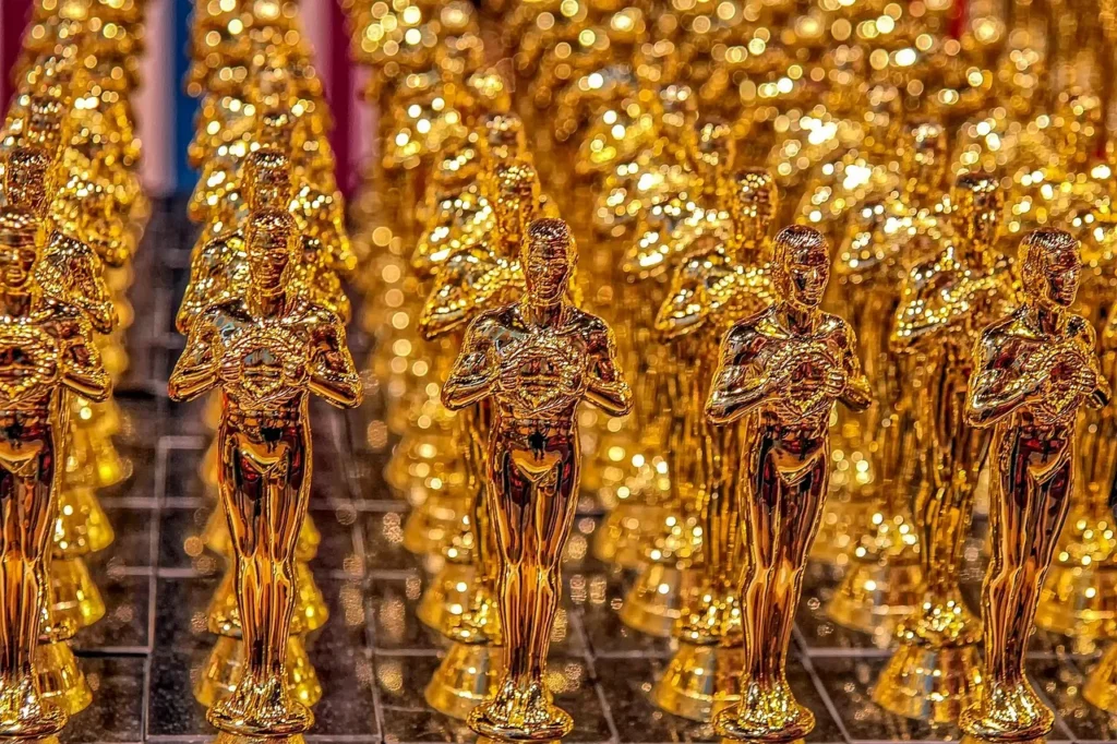 A close-up shot of multiple golden Oscar statuettes, arranged in rows, reflecting light.