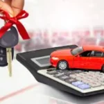 Hand holding car keys with red bow, miniature red car, and calculator, symbolizing affordable auto loans and smart car financing.