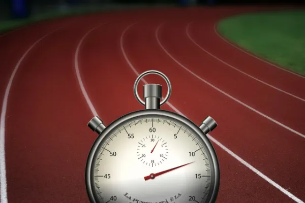 A classic analog stopwatch with its hands showing time, superimposed in the foreground over a blurred red running track, symbolizing the measurement of personal timing and progress.