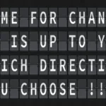 A black split-flap display showing the white text: "TIME FOR CHANGE IT IS UP TO YOU WHICH DIRECTION YOU CHOOSE !!!"