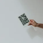 A hand holds a white Kindle displaying a screen filled with various letter forms and typographic elements.