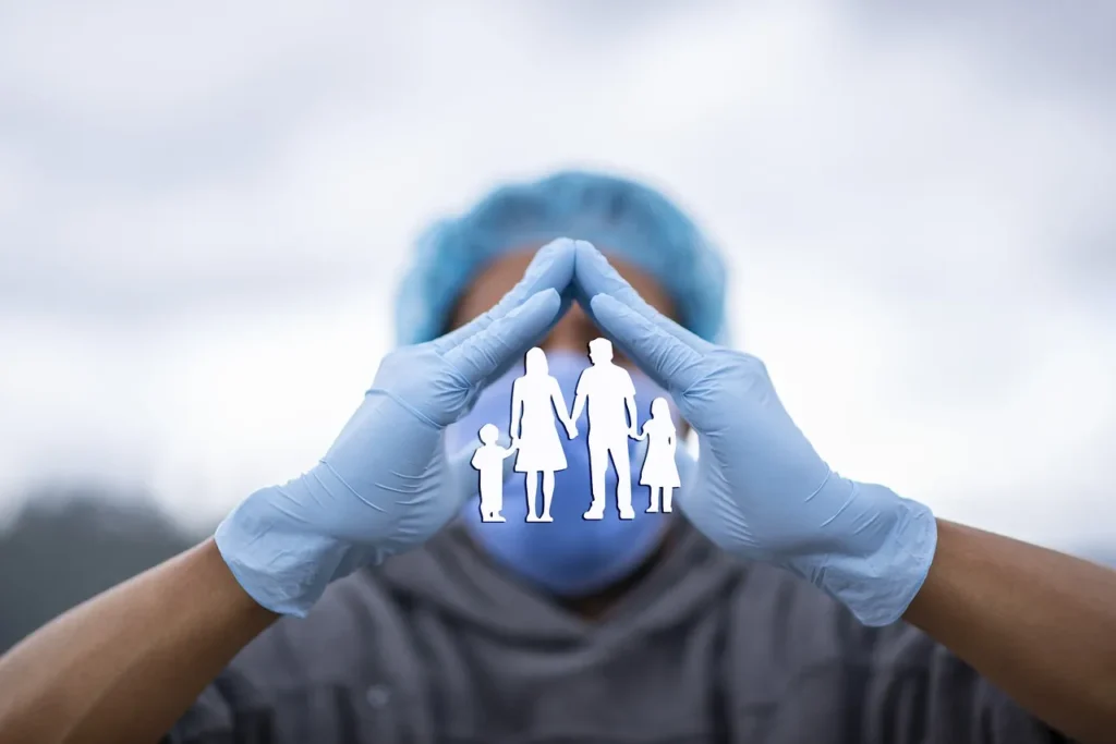 Hands of a family holding a paper heart with a visible heartbeat line on a teal background, symbolizing health, care, and financial protection.