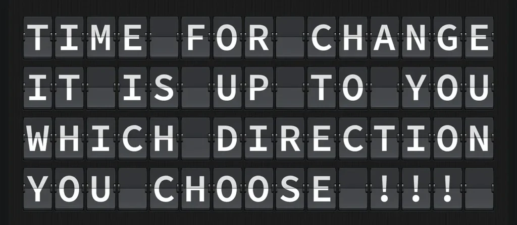 A vintage-style flip board sign displaying the inspiring message: "TIME FOR CHANGE IT IS UP TO YOU WHICH DIRECTION YOU CHOOSE !!!"