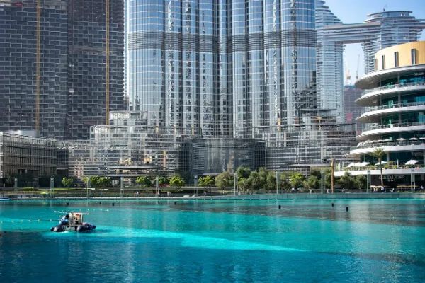 A vibrant turquoise waterfront area in Dubai, featuring modern high-rise buildings including the Burj Khalifa and surrounding architecture, not directly related to JBR.