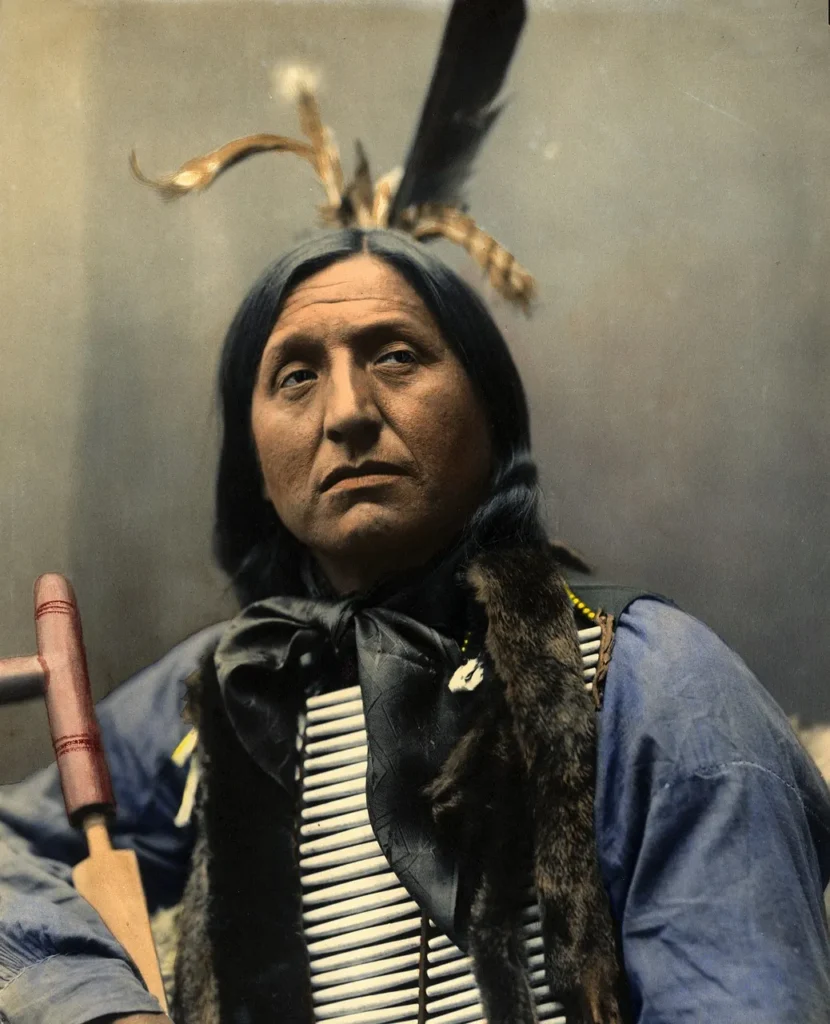 A vintage-style portrait of a Native American chief with a serious expression, holding a peace pipe.